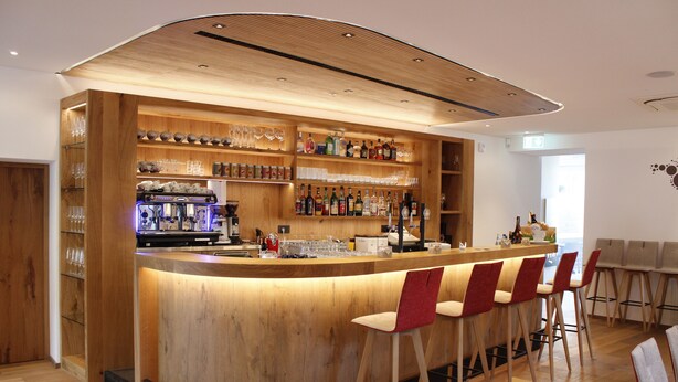 A modern bar area with wooden shelves, bar stools, and a variety of bottles and glasses. - Hotel Ristorante-Pizzeria Al Cervo (Magre sulla Strada del Vino)