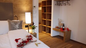 A hotel room with a bed, bedside table, lamp, and a wooden shelf with wine bottles. - Hotel Ristorante-Pizzeria Al Cervo (Magre sulla Strada del Vino)