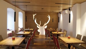A modern dining area with wooden tables and chairs, a central light sculpture, and a wooden ceiling. - Hotel Ristorante-Pizzeria Al Cervo (Magre sulla Strada del Vino)