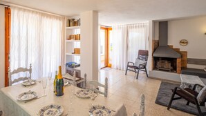 A dining area with a table set for two, a bookshelf, a fireplace, and a view through a doorway. - House on the beach with sea view (Tossa de Mar)