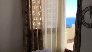 A bedroom with a bed, a window with curtains, and a view of the sea. - House on the beach with sea view (Tossa de Mar)