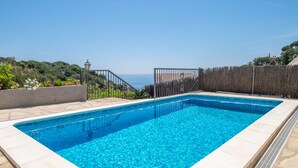 A rectangular swimming pool with clear blue water, surrounded by a stone deck and a wooden fence. - House on the beach with sea view (Tossa de Mar)
