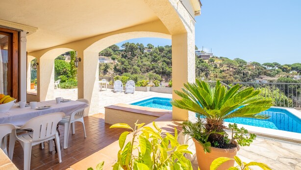 A terrace with a pool, outdoor seating, and a view of a hillside. - House on the beach with sea view (Tossa de Mar)