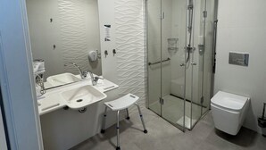 A modern bathroom with a glass-enclosed shower, a double sink, and a toilet. - Hotel Carina (Tczew)