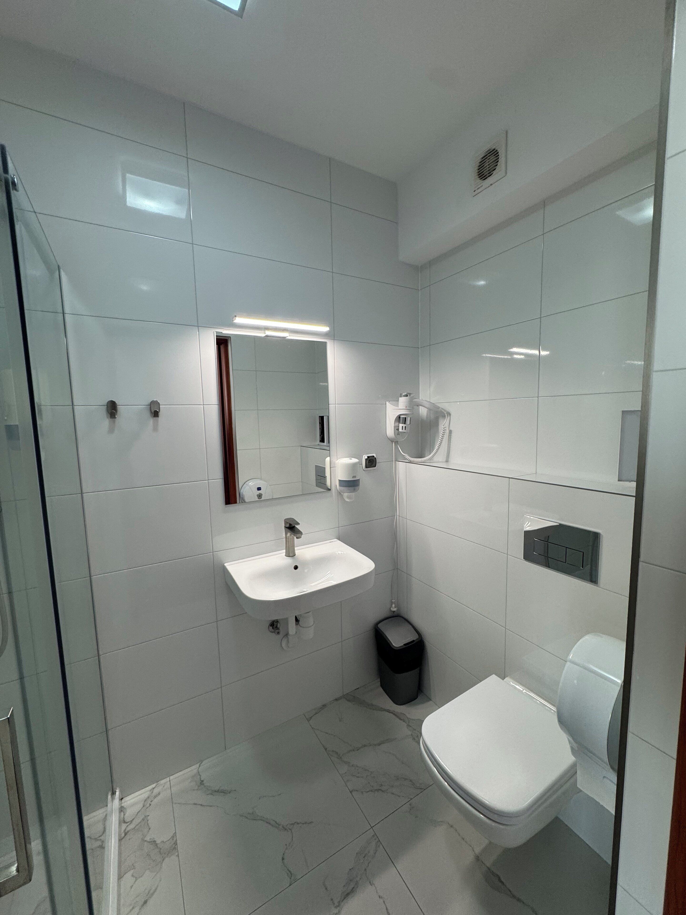 Een moderne badkamer met een witte wastafel, spiegel en toilet.