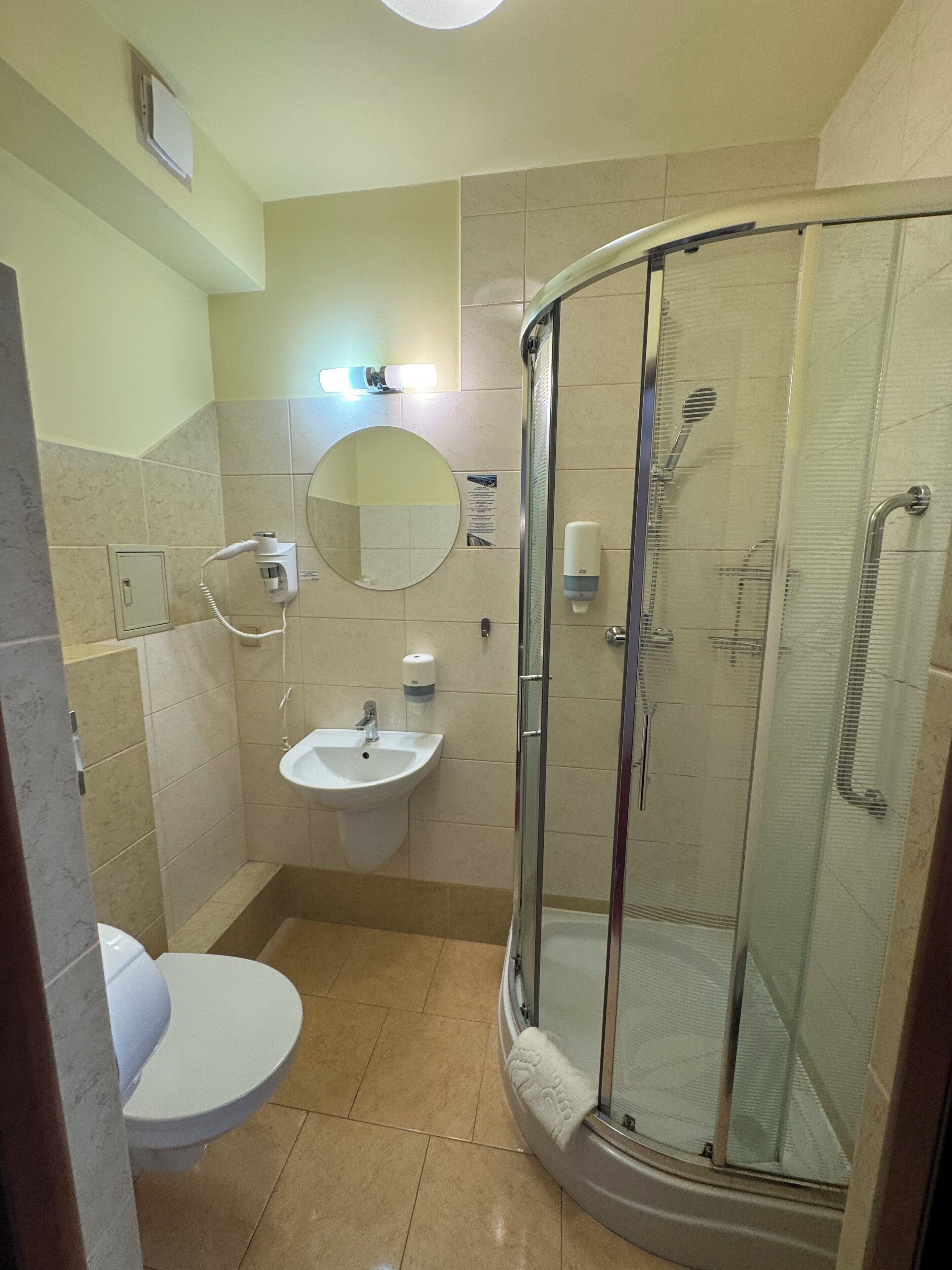 A bathroom with a glass-enclosed shower, a sink, and a toilet.