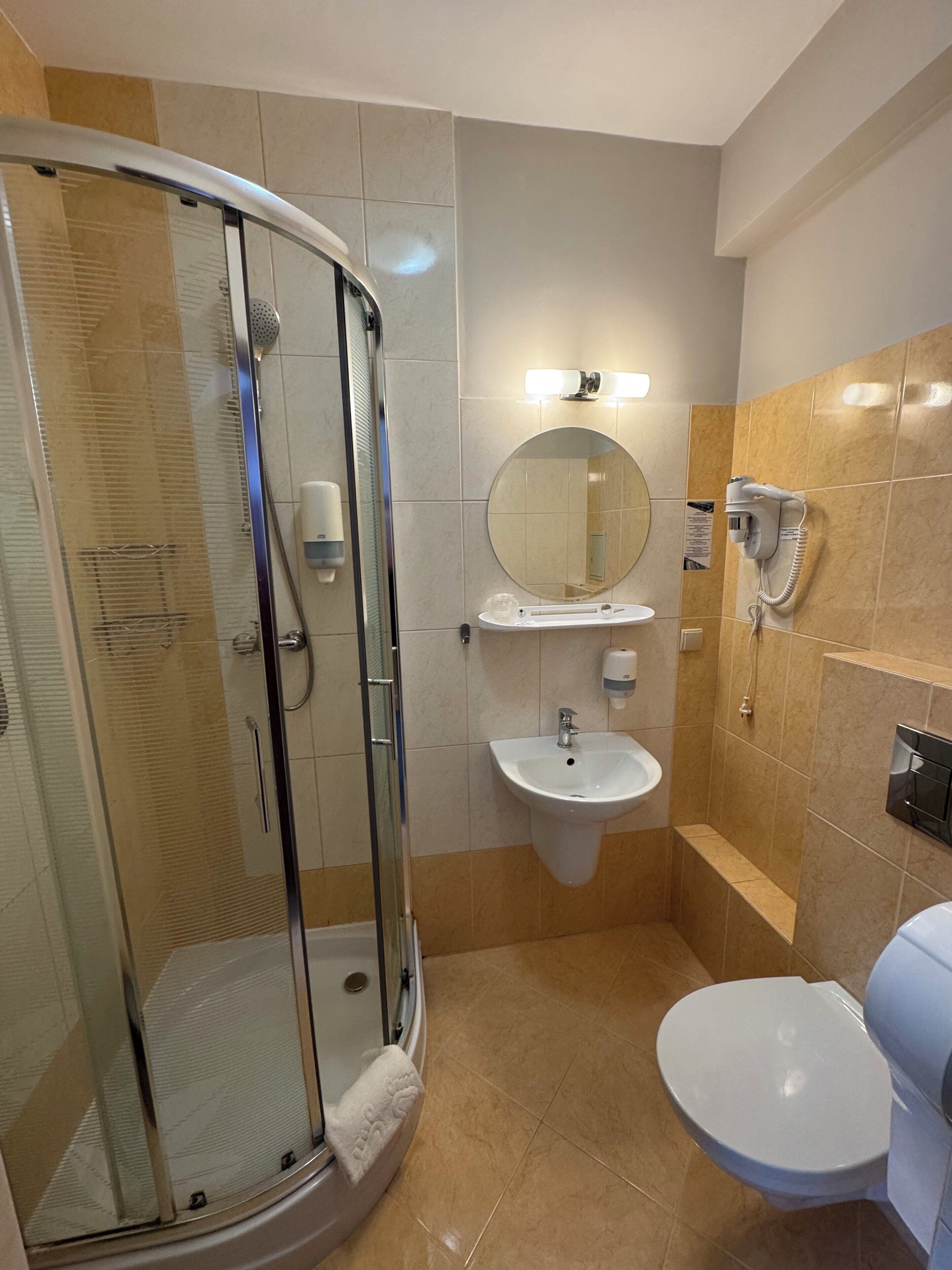 Une salle de bain avec une douche à parois de verre, un lavabo, des toilettes et un miroir.