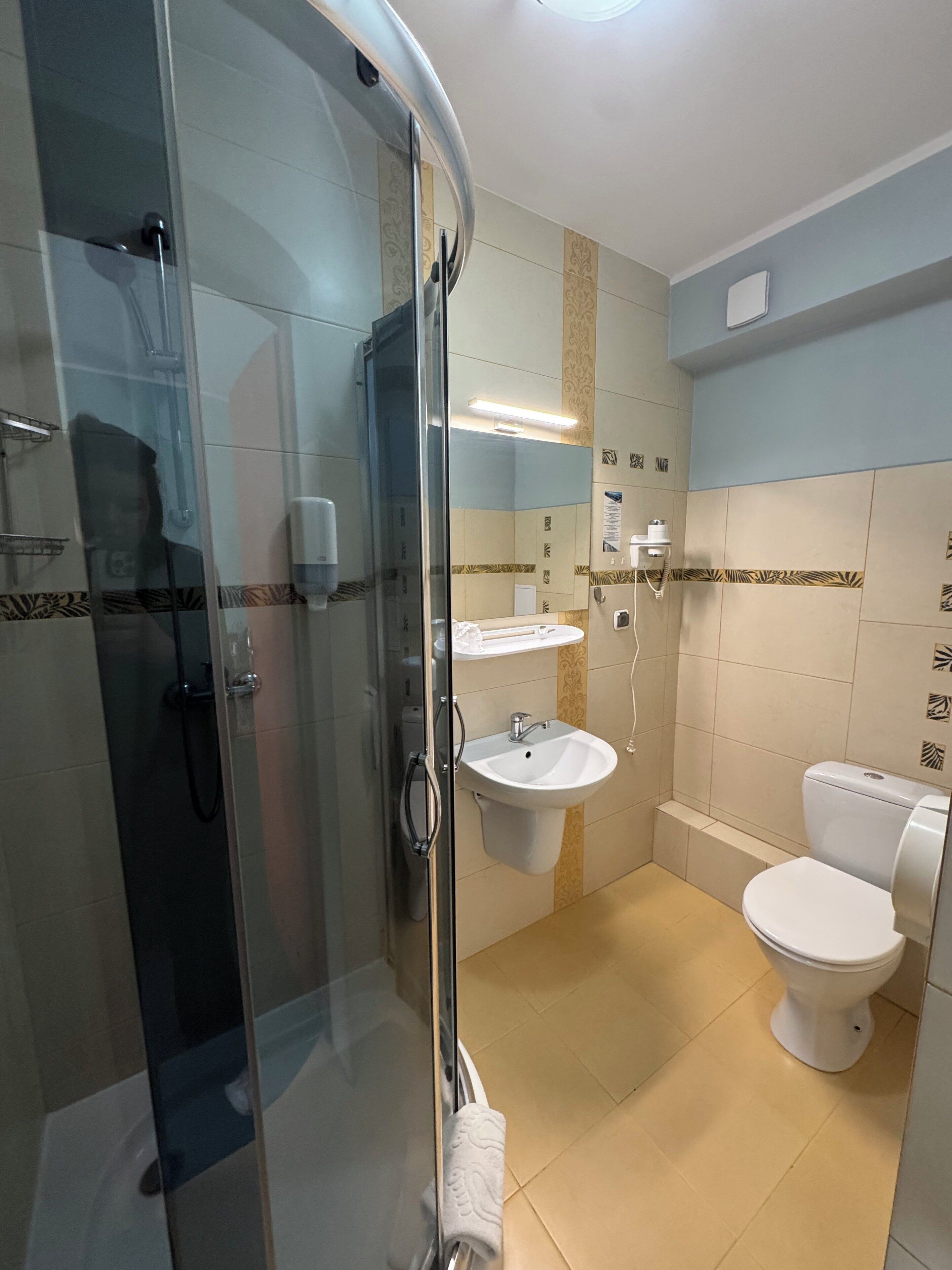 Un baño moderno con ducha de vidrio, lavamanos e inodoro.