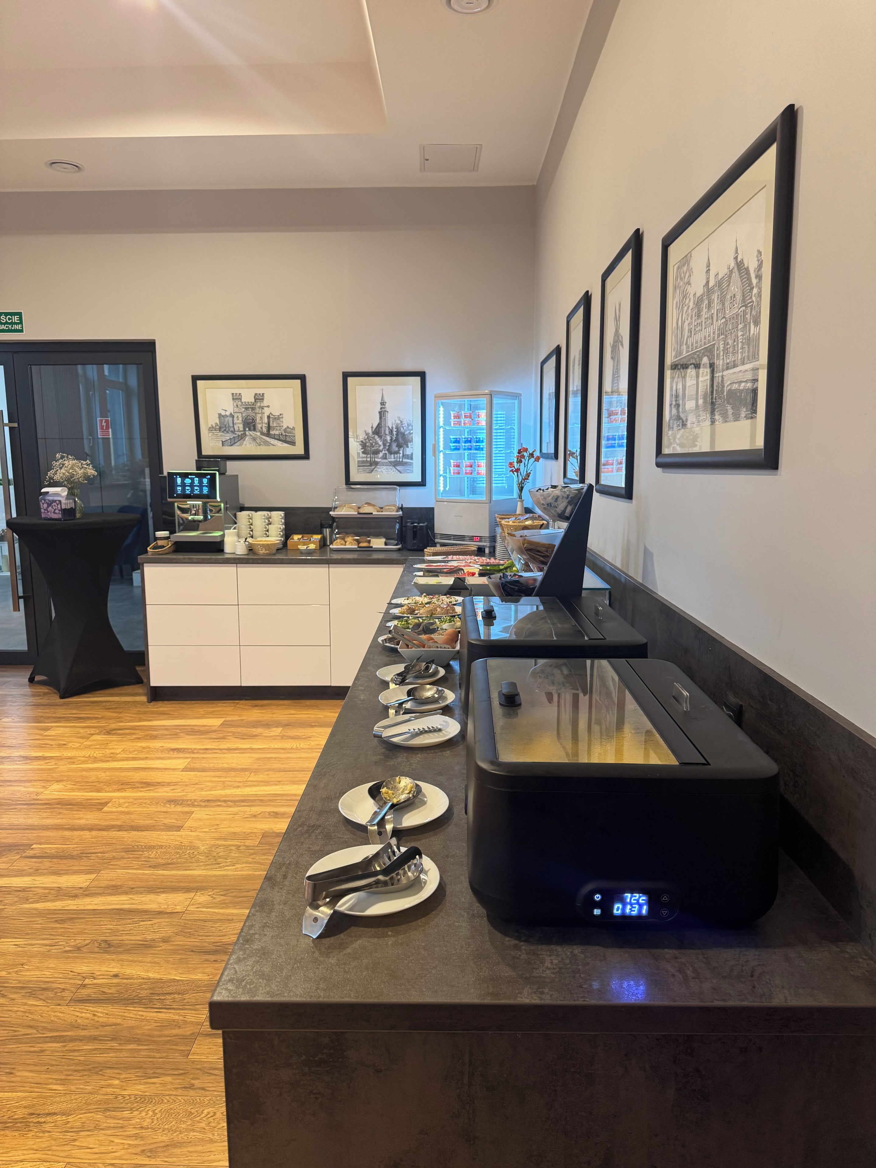 A buffet setup with a variety of food items, a coffee machine, and a digital clock displaying the time.