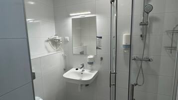 A modern bathroom with a glass-enclosed shower, a white sink, and a toilet.