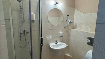 Un baño moderno con ducha envuelta en vidrio, lavamanos, inodoro y espejo.