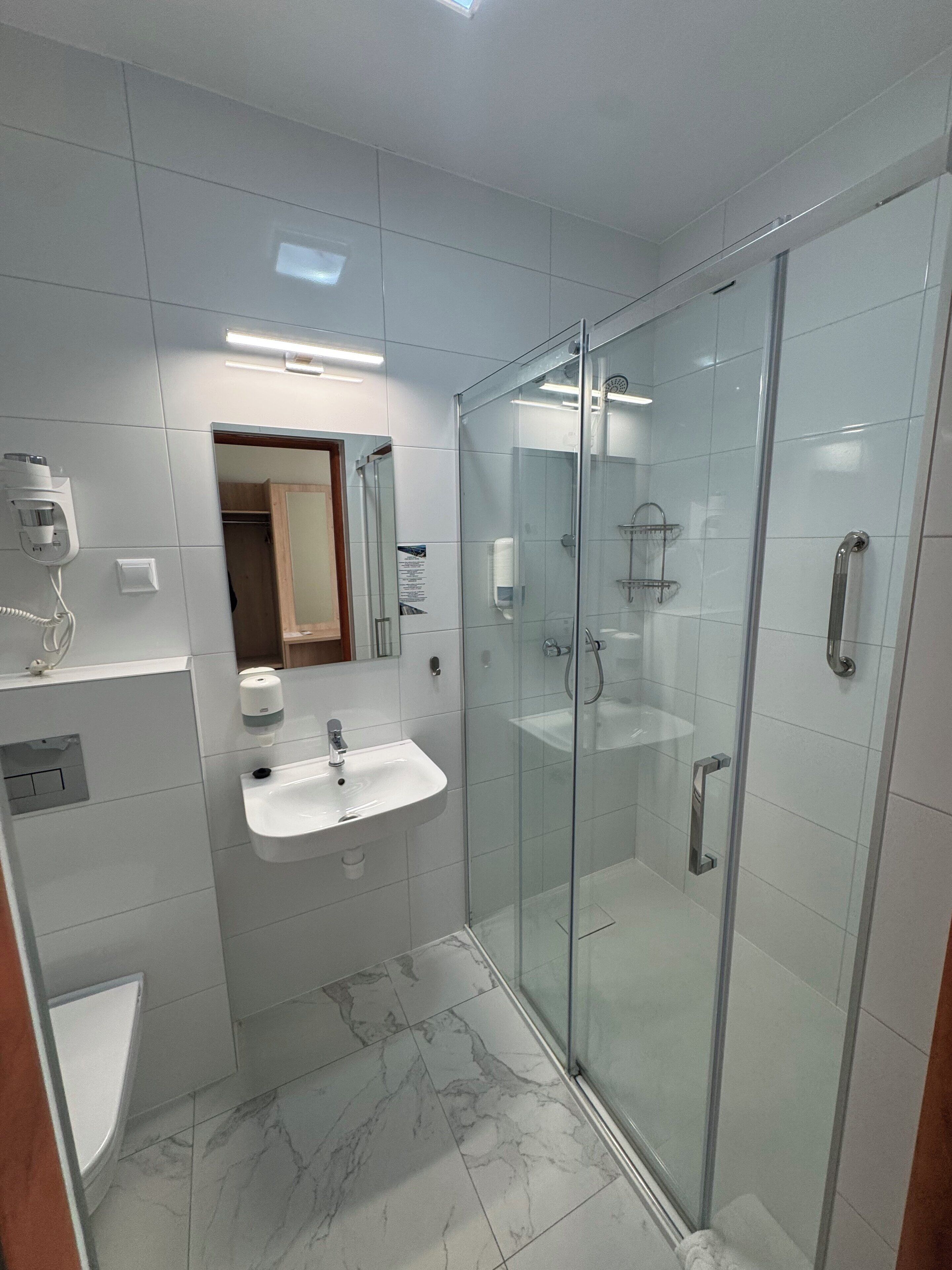 A modern bathroom with a glass-enclosed shower, a white sink, and a mirror above it.