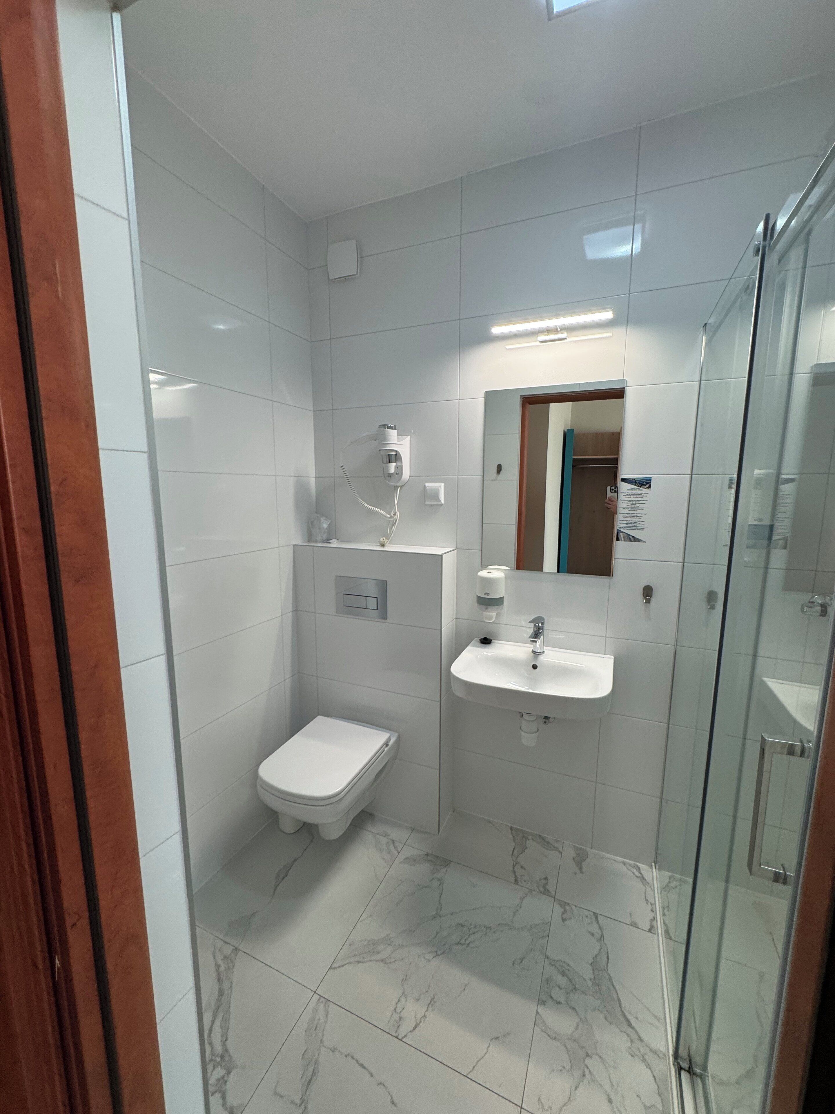 Un baño moderno con inodoro, lavamanos y ducha.