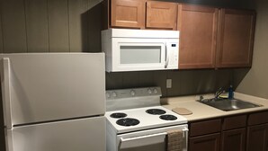 Una cocina equipada con refrigerador, estufa, microondas y gabinetes de madera.
