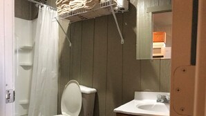 Un baño con inodoro, lavamanos y un cubo de basura.
