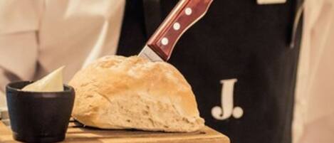 A loaf of bread on a wooden board with a knife and a black cup beside it.