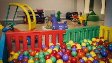 Kids can play and explore in this vibrant play area featuring a ball pit and fun toys.