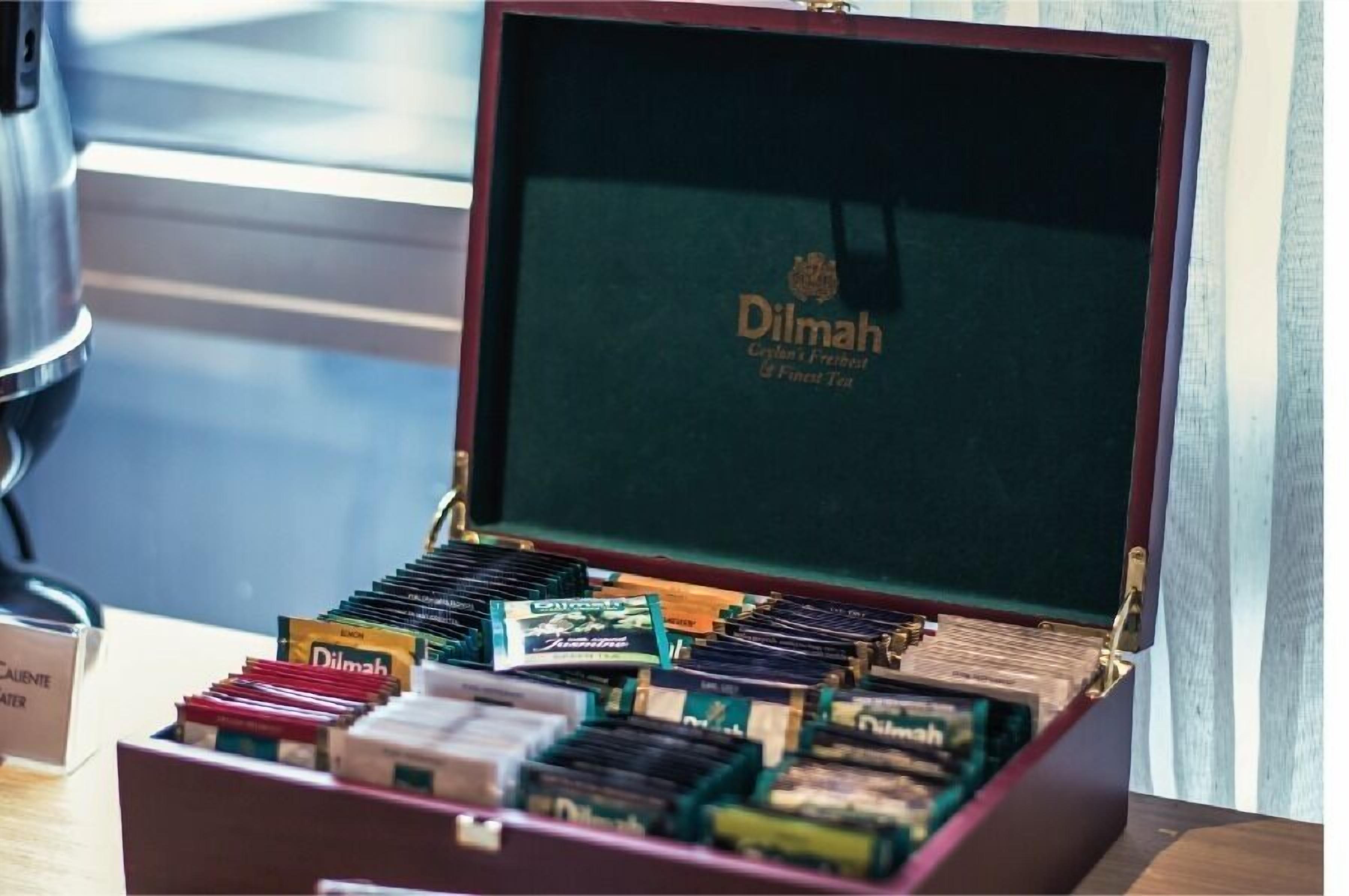 Een verzameling Dilmah theekistjes in een houten doos met een groene binnenkant.