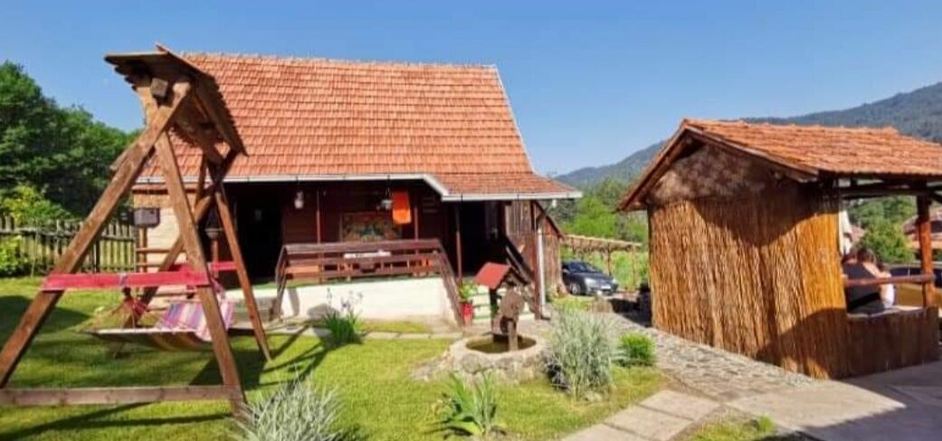 Ein rustikales Holzhaus mit rotem Ziegeldach, einer Schaukel und einem kleinen Garten.