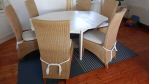 A dining area with a round table and four wicker chairs tied with white ribbons.