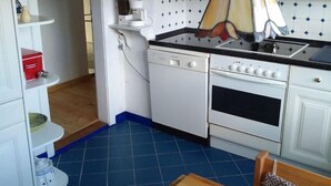 A compact kitchen with white cabinets, a stove, and a coffee maker.
