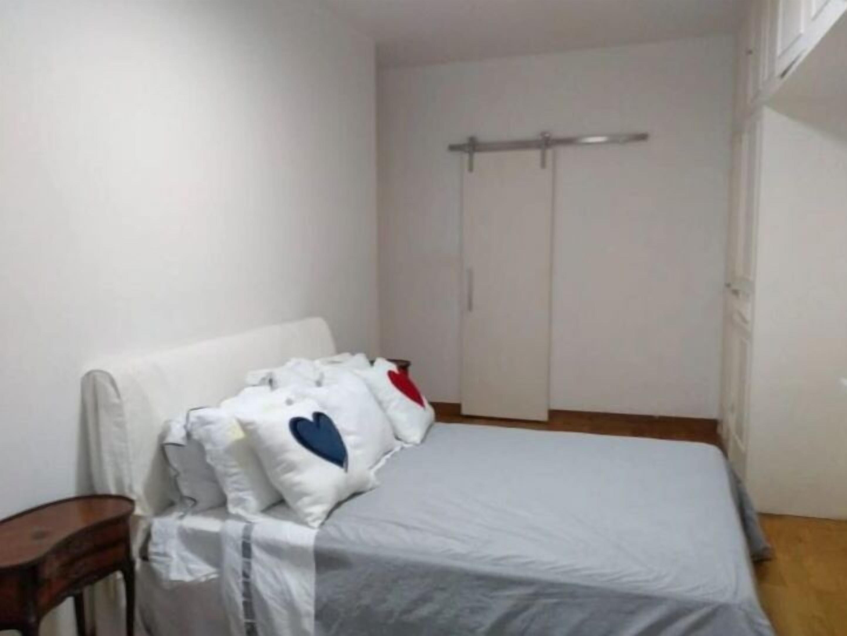 A bedroom with a bed, a nightstand, and a wardrobe.