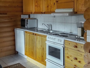 Una cucina con mobili in legno, un forno a microonde, un lavandino, un fornello e un tostapane.