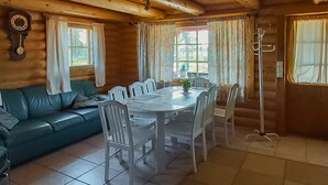 A wooden cabin interior with a dining table, chairs, a sofa, and a coat rack. - Harjurinne by Interhome (Lestijärvi)