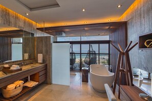 A modern bathroom with a large mirror, wooden vanity, and a freestanding bathtub.