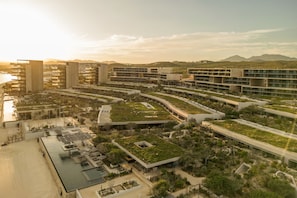 A modern hotel complex with multiple buildings, rooftop gardens, and a marina.