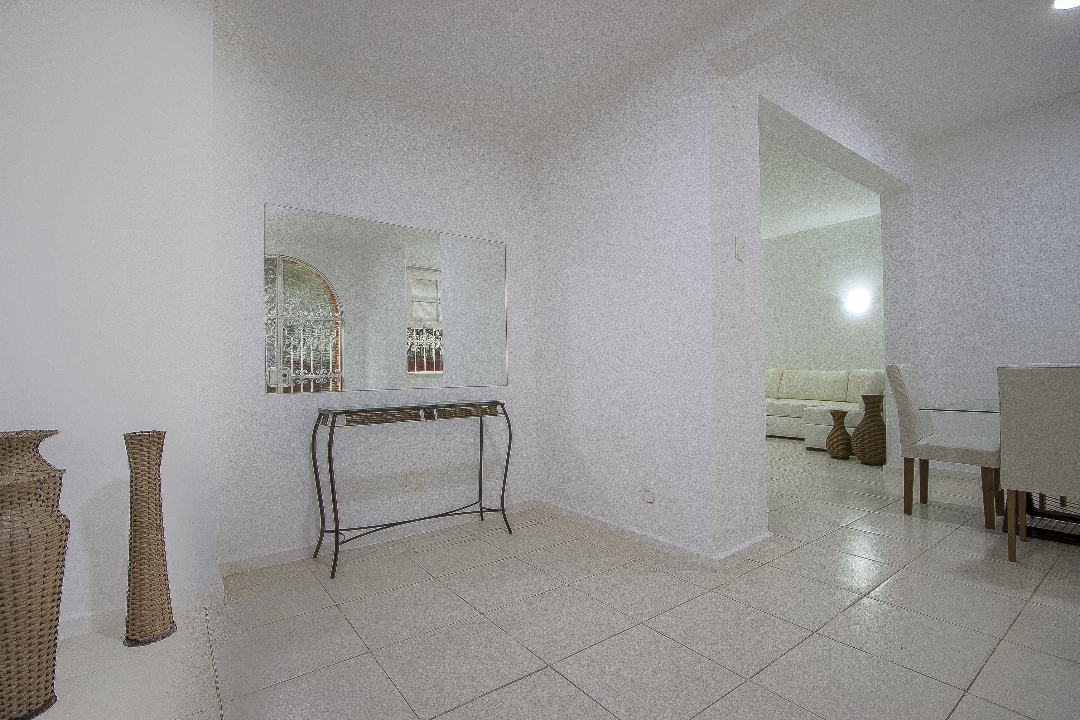 A minimalist living room with a large mirror, a glass-top table, and a white sofa.