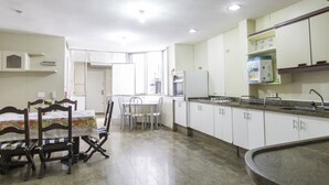 A kitchen with a dining table and chairs, a refrigerator, and a sink. - LineRio Vista Mar Copacabana 460 (Rio de Janeiro)