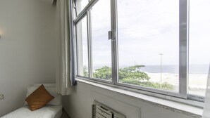 A room with a bed, a window with a view of the beach, and a radiator. - LineRio Vista Mar Copacabana 460 (Rio de Janeiro)