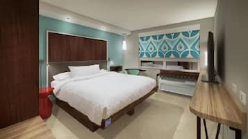 Una habitación de hotel moderna con una cama grande, un escritorio, una silla y un televisor.