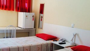 A room with two beds, a desk, a chair, a telephone, and a lamp. - Capivari Centro Hotel (Capivari)