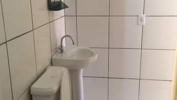 Un baño pequeño y limpio con azulejos blancos, un inodoro, un lavabo y un espejo.