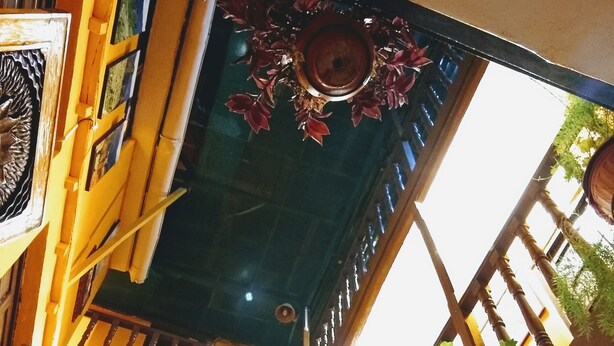A multi-level atrium with wooden railings, potted plants, and a decorative ceiling. - International Hostels (Cusco)