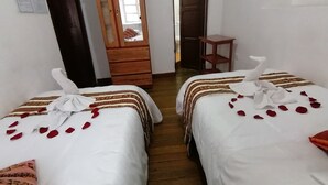 A hotel room with two beds, each adorned with white linens and red rose petals. - International Hostels (Cusco)
