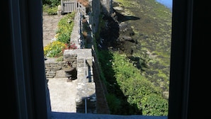 A coastal view through a window, featuring a stone wall, a wooden fence, and a clear blue sky. - The waterfront Maison des Seigneurs (Le Conquet)
