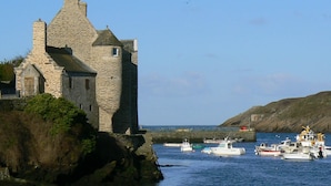 A stone castle by the sea with boats docked nearby. - The waterfront Maison des Seigneurs (Le Conquet)