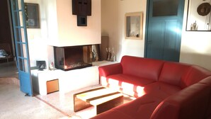 Uma sala de estar com um sofá vermelho, uma lareira e uma porta azul.
