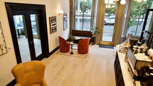 A hotel lobby with a seating area, a reception desk, and a view of the street through large windows. - Harlow Hotel (Portland)