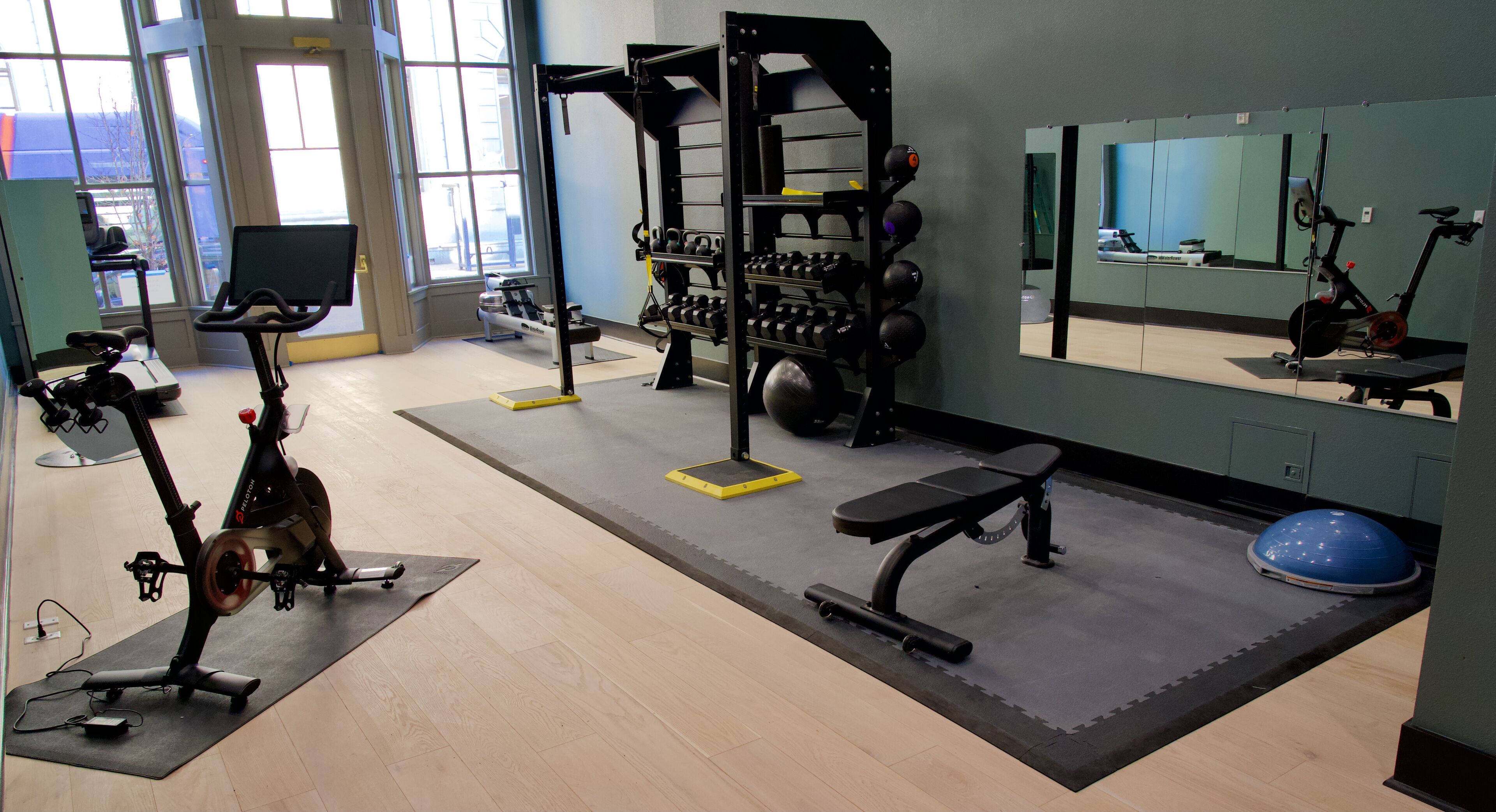 Un gimnasio con equipo de ejercicio, un espejo y vistas al exterior.