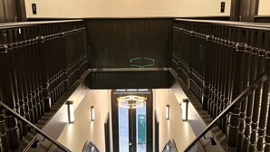A modern hotel lobby with a central staircase, a geometric chandelier, and a patterned carpet. - Harlow Hotel (Portland)
