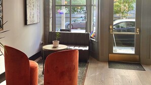 A modern interior with a seating area, large windows, and a view of the street. - Harlow Hotel (Portland)