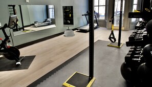 A gym with exercise equipment, a mirror, and a window. - Harlow Hotel (Portland)