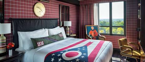 Ein Hotelzimmer mit einem großen Bett, Blick auf die Stadt und einem Bild an der Wand.
