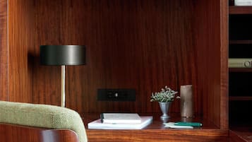 A wooden desk with a lamp, a vase with flowers, and a book.