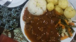 Et bord med tallerkener med mad, blandt andet ris og kartofler, samt en flaske sauce.