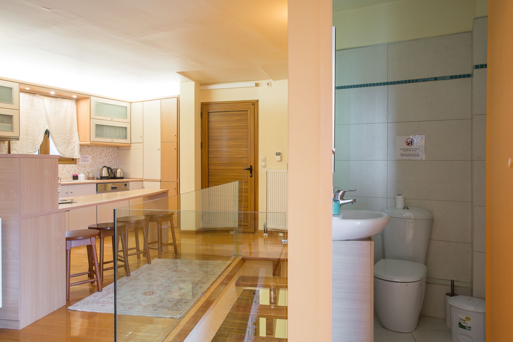 Una cocina moderna con armarios de madera, un microondas integrado y un pequeño comedor con taburetes.